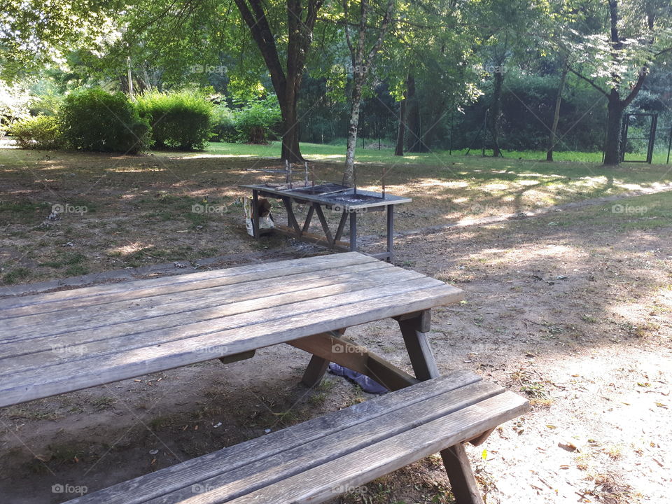 Wooden table and bench near bbq place in the park