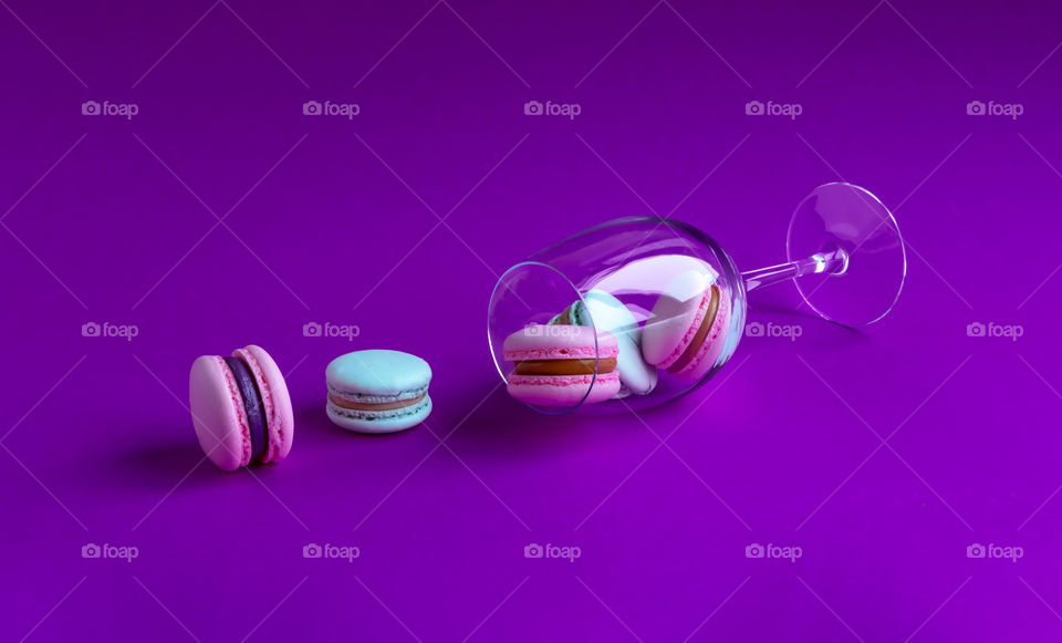 Macarons with cream in the glass on purple background.