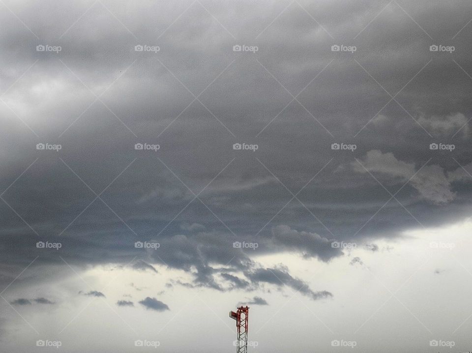 A photo of dark clouds in a winter day with a metal construction peaking right in the middle