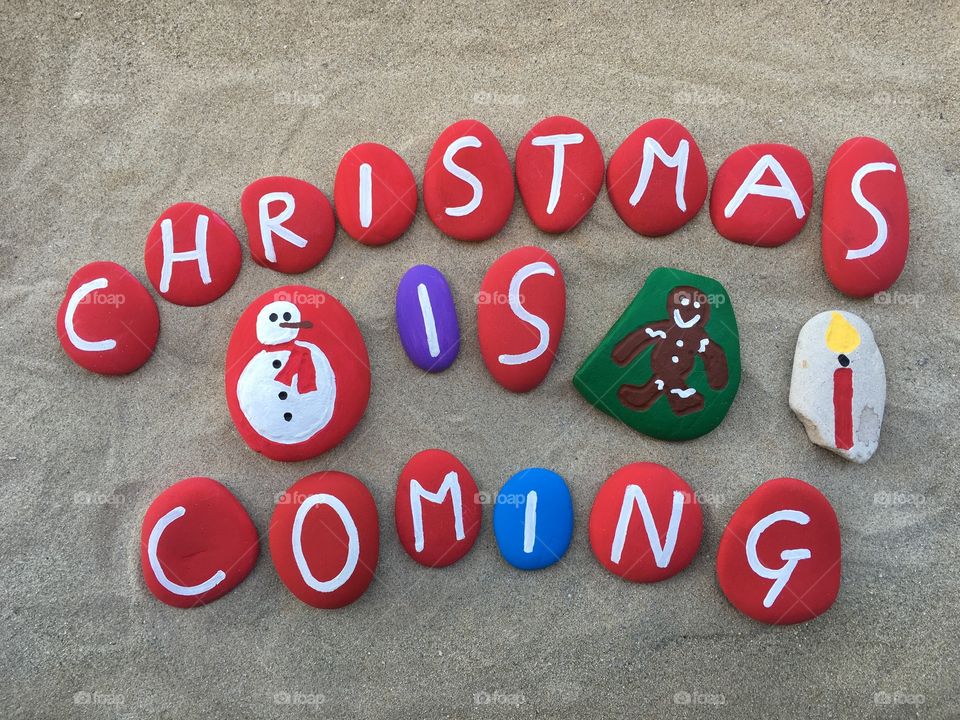 Christmas is coming, colored stones composition with gingerbread, snowman and a candle