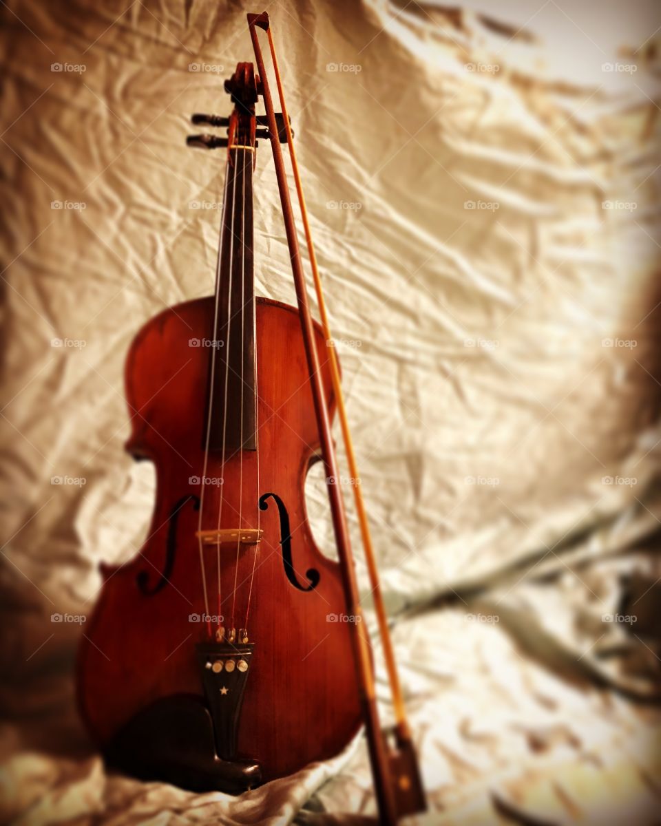 Old violin with bow against light background. 