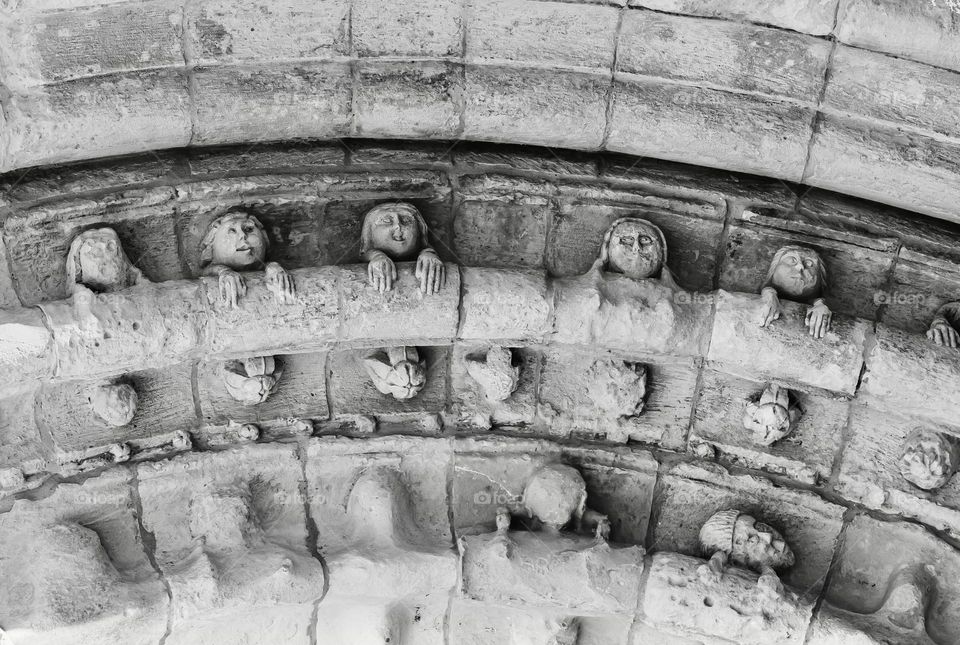 Stone faces carved on the mediaeval cornice over the door of Igreja de São Pedro, Leiria, Portugal 