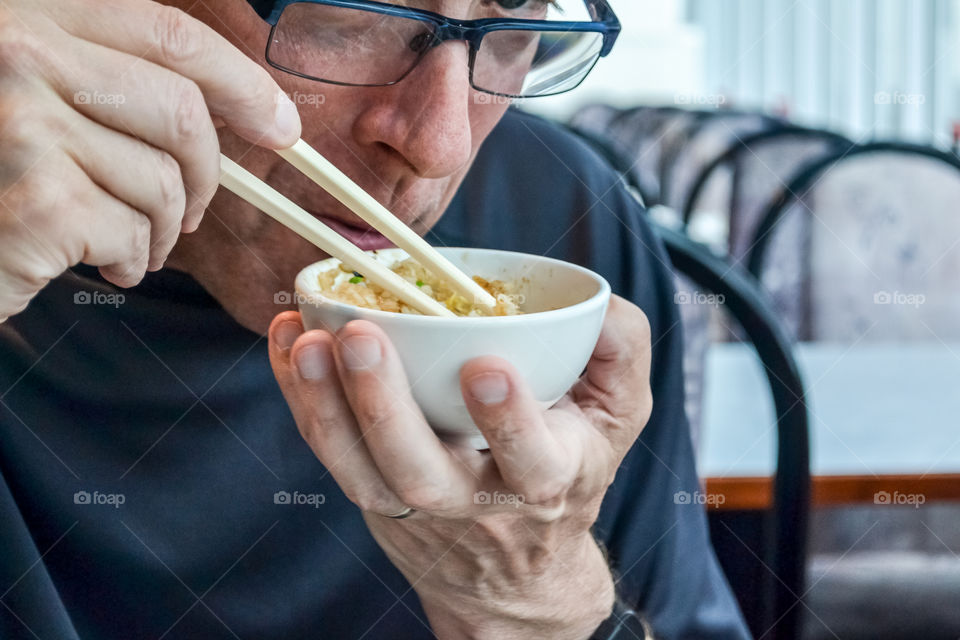 Man eating food with chopstick in bowl