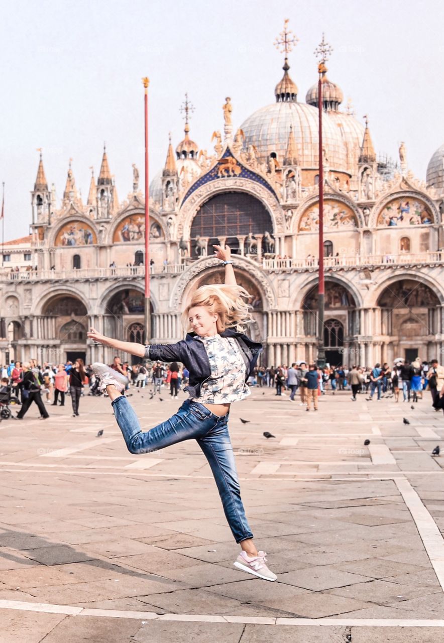 Happy young woman jumping in Venice square