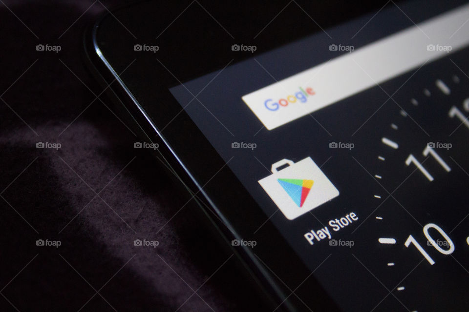 Close-up of a tablet with Google Store icon app and clock on display macro shot