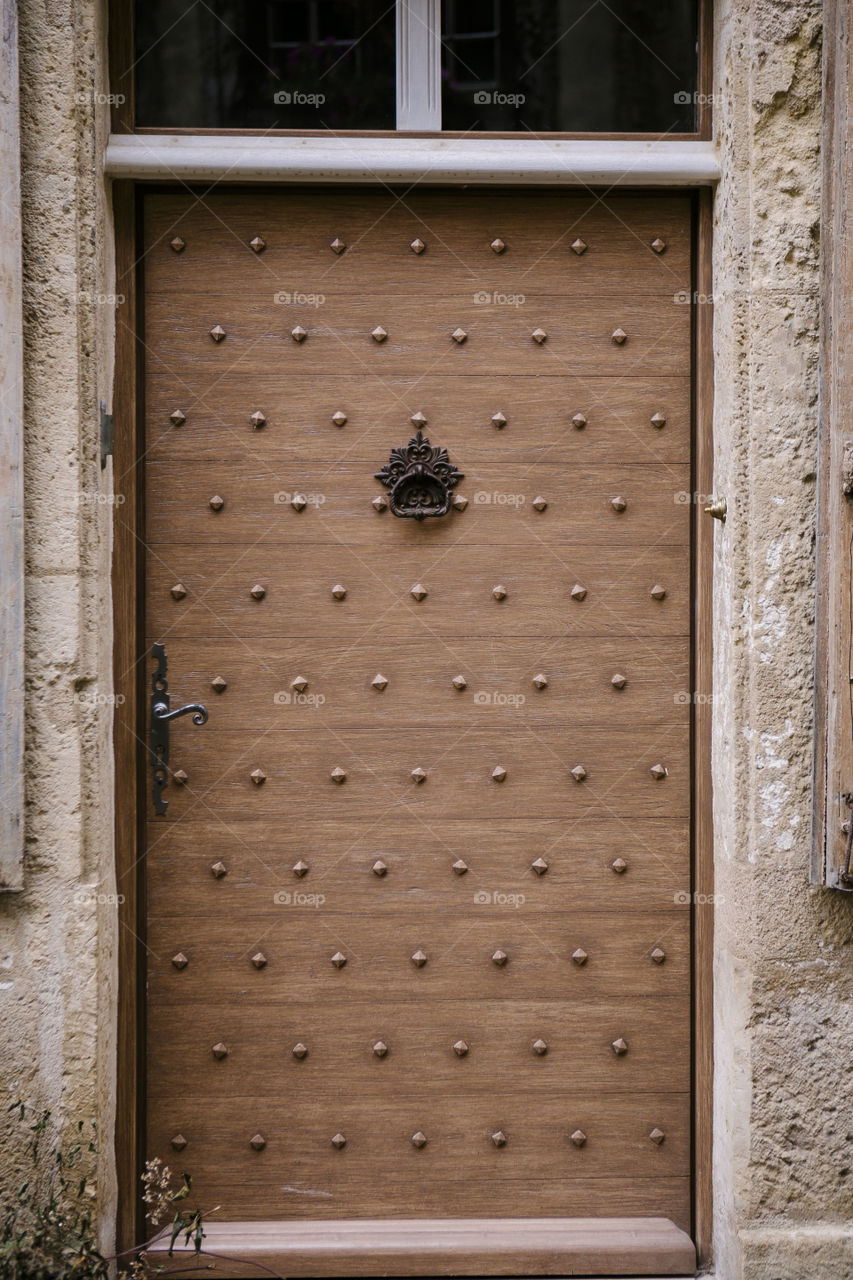 Ornate wooden door in French countryside with brass knocker 