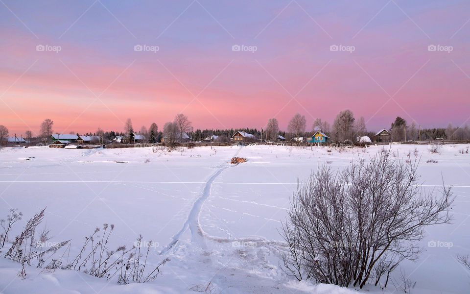 Small Russian village on the shore of the river. Clear cold winter morning