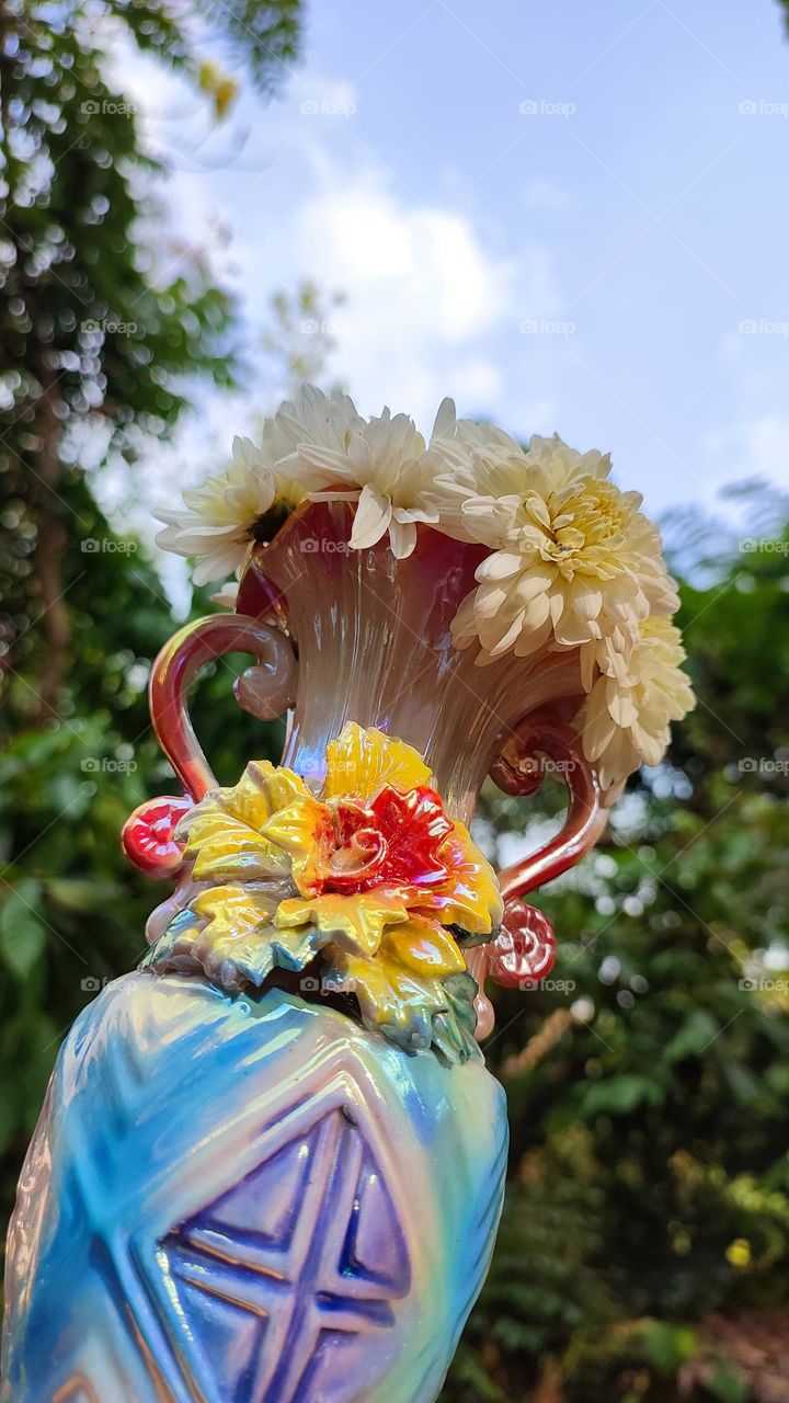 Beautiful white flowers in a colourful flowerpot with a flower sculpture