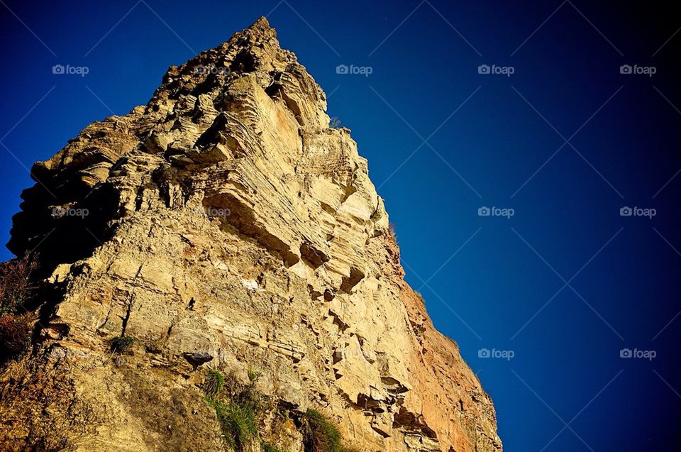 An eroded sandstone cliff against a deep blue sky