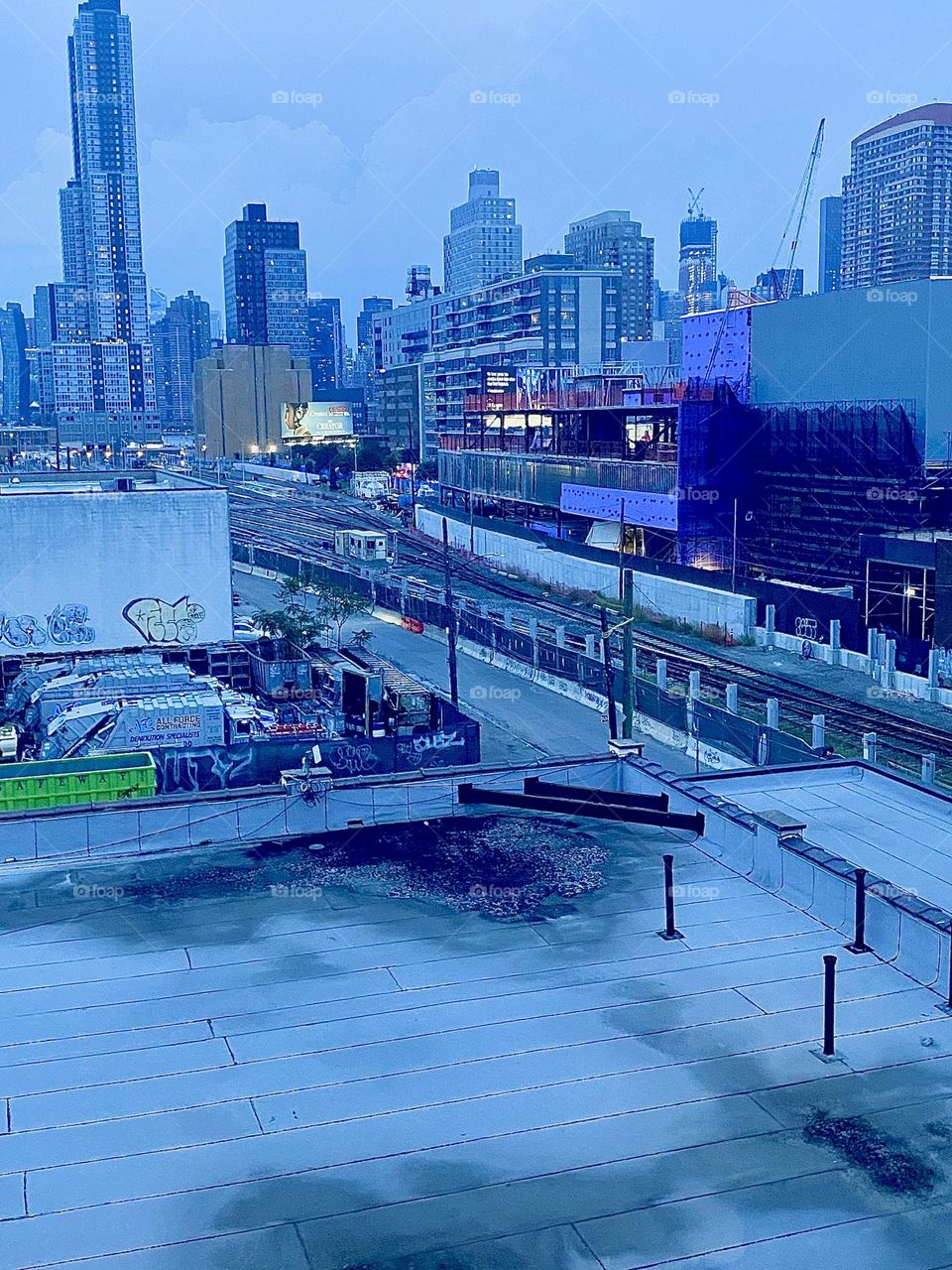 This is the view from the staircase of the “Pulaski Bridge” at “Newtown Creek” in LIC, Queens overlooking the LIRR, the “Long Island Railroad” train tracks. In the far distance you can see “Manhattan”. 2023. Hypnotic Productions