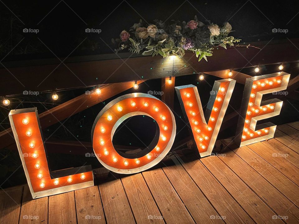 Illuminated sign spelling the word Love lit up at night outdoors 