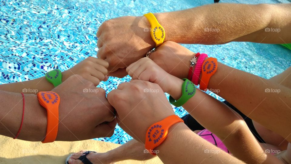 Hands and cams with bright bracelets in the pool