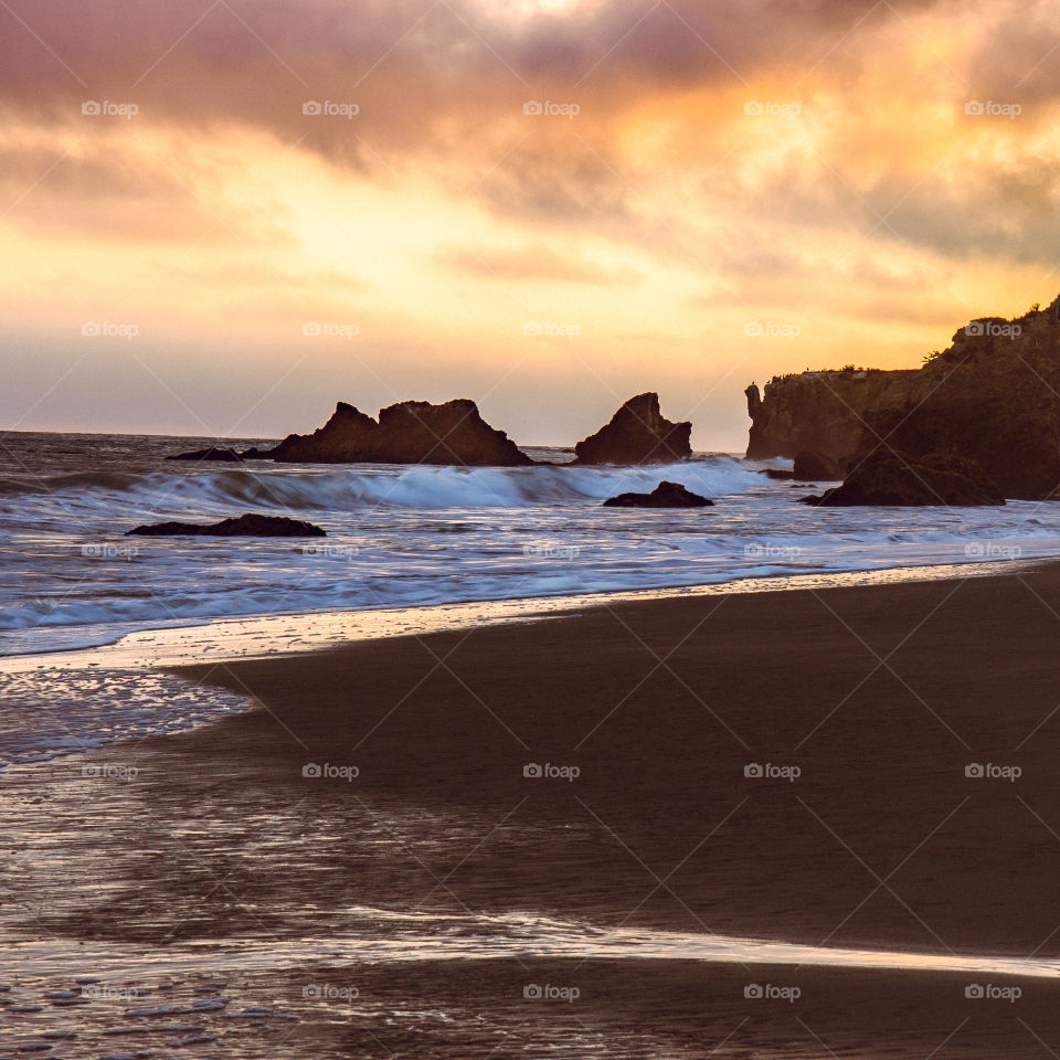 Sunset at the beach in Malibu California America with rocks and crashing waves. West Coast Pacific water. Perfect for surfing.