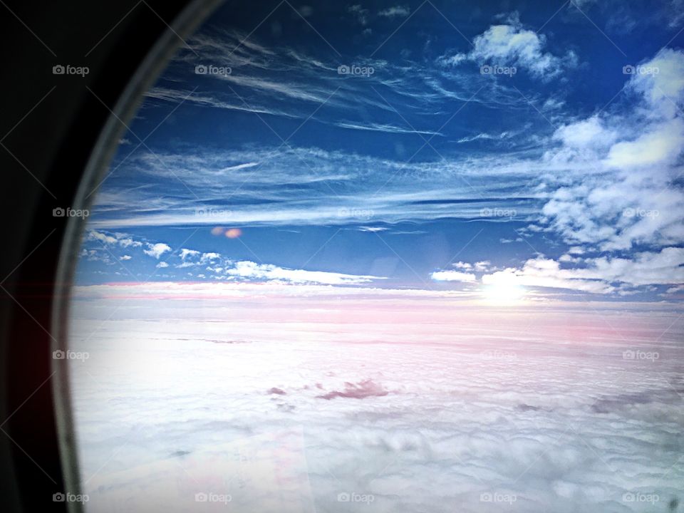 Airline window with a view of the magical cloudscape.