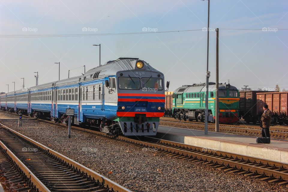 The train arrives at the station. A man is waiting for a train on the platform.