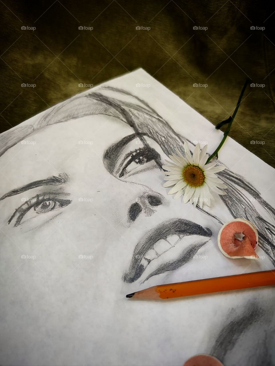 The girl's face drawn in pencil.  There is a chamomile and a pencil on the sheet with the portrait.