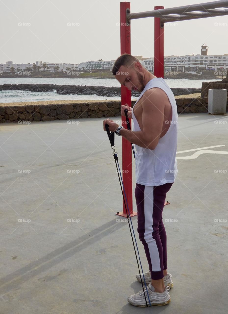 chico joven entrenando en la calle en exteriores, usando bandas elásticas y realizando ejercicios variados
