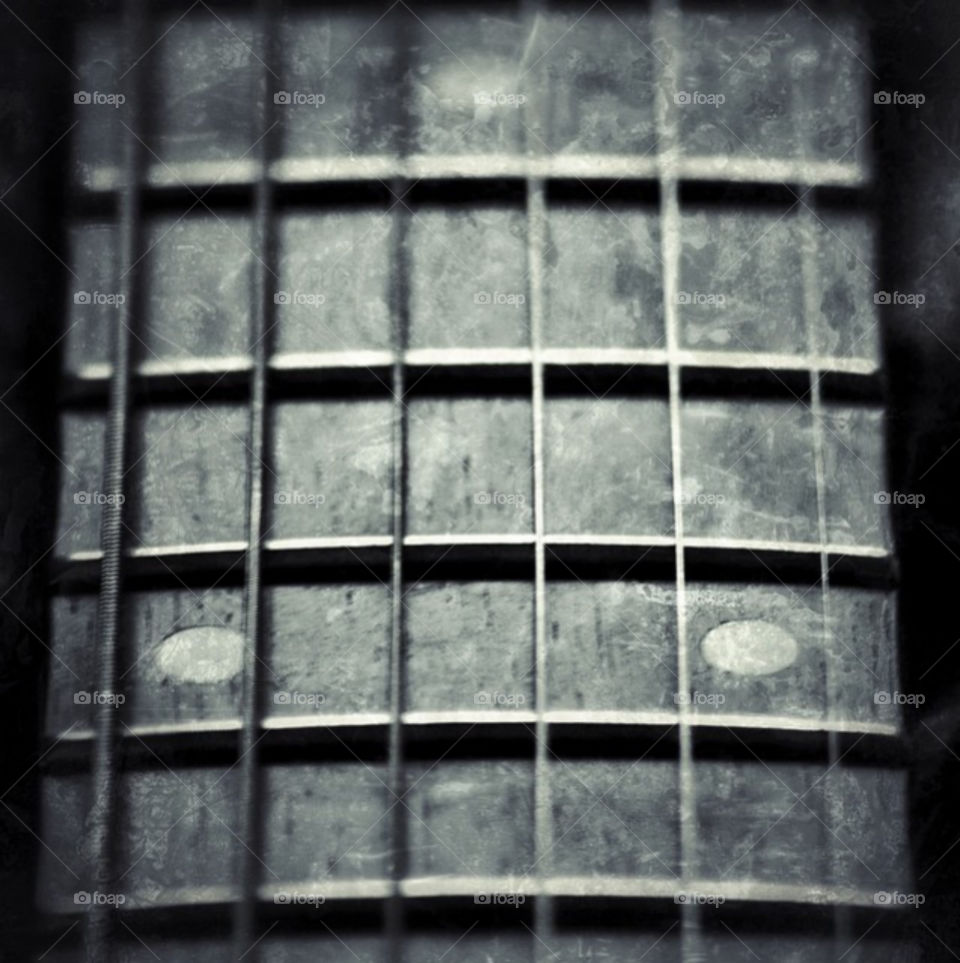 Black and white close-up of the worn neck of a vintage acoustic guitar.