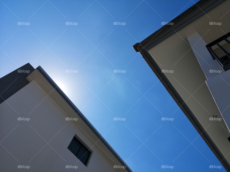 Below angle of roof and building with sunshine sky.