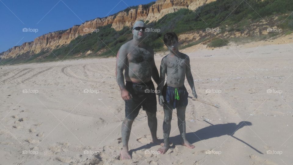 Father and son standing on sand