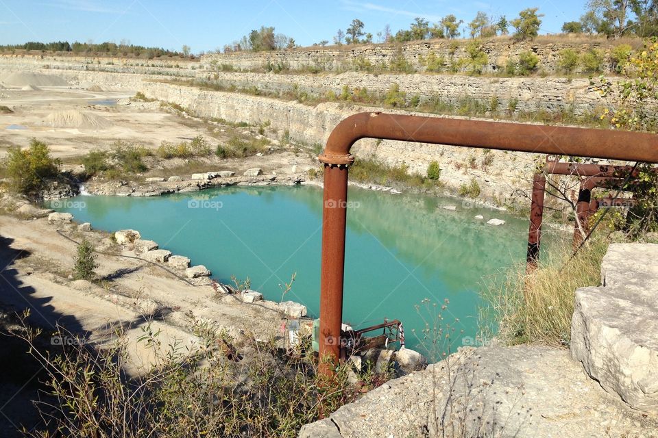 Quarry . Rusty pipes and turquoise pool in limestone quarry