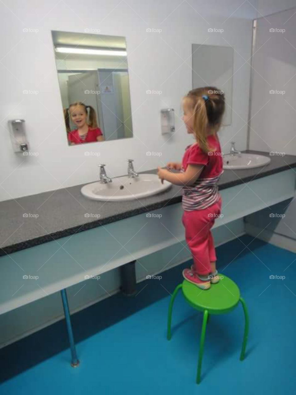 little girl using the ladies rest room and checking out her reflection