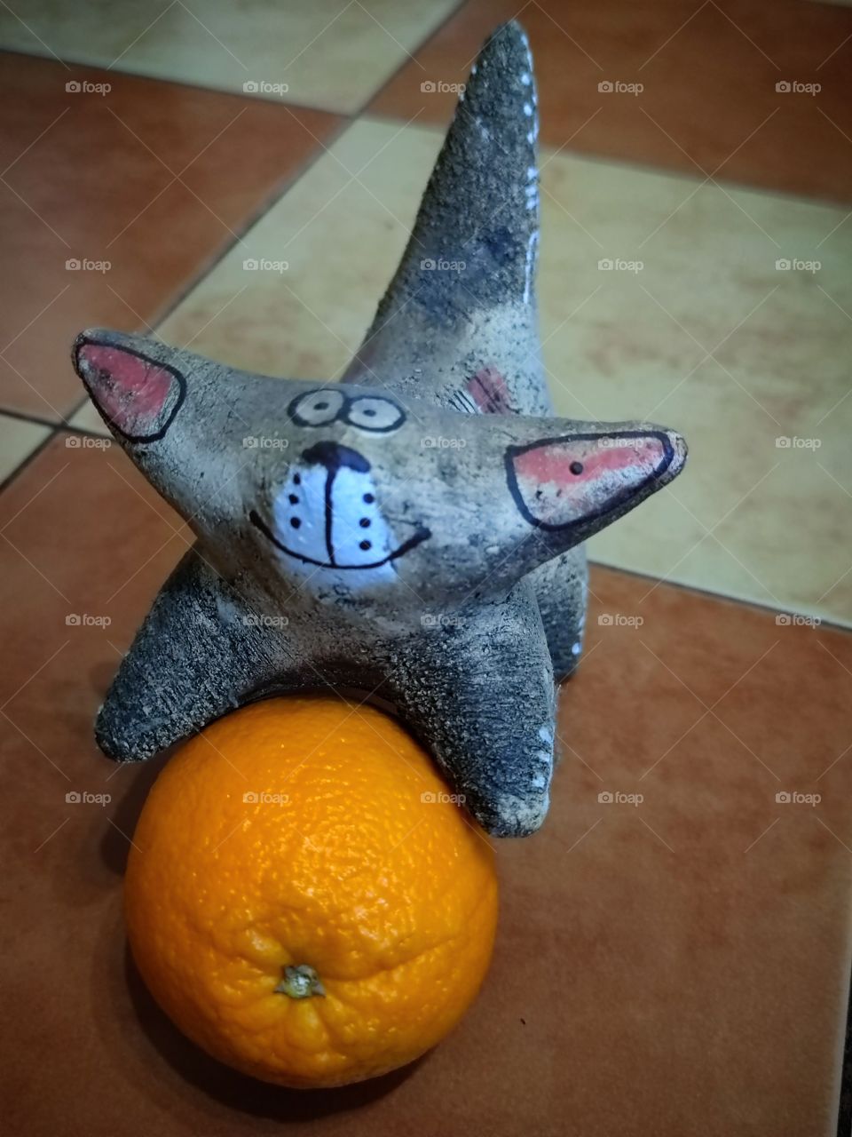 Clay cat figurine on orange