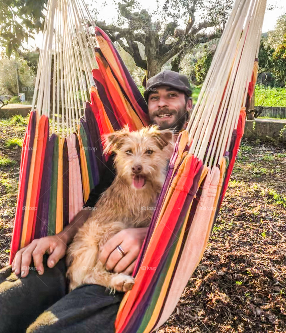This dog is happily swinging in a hammock with her owner