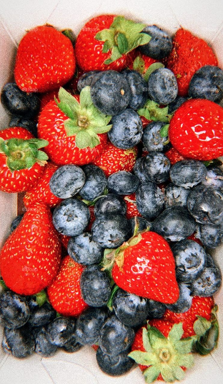 Berry fantasy.  Red strawberries with green leaves and black blueberries