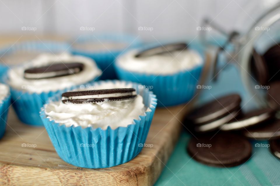 Oreo cookie ice cream cupcakes on a wooden board and white and blue background 