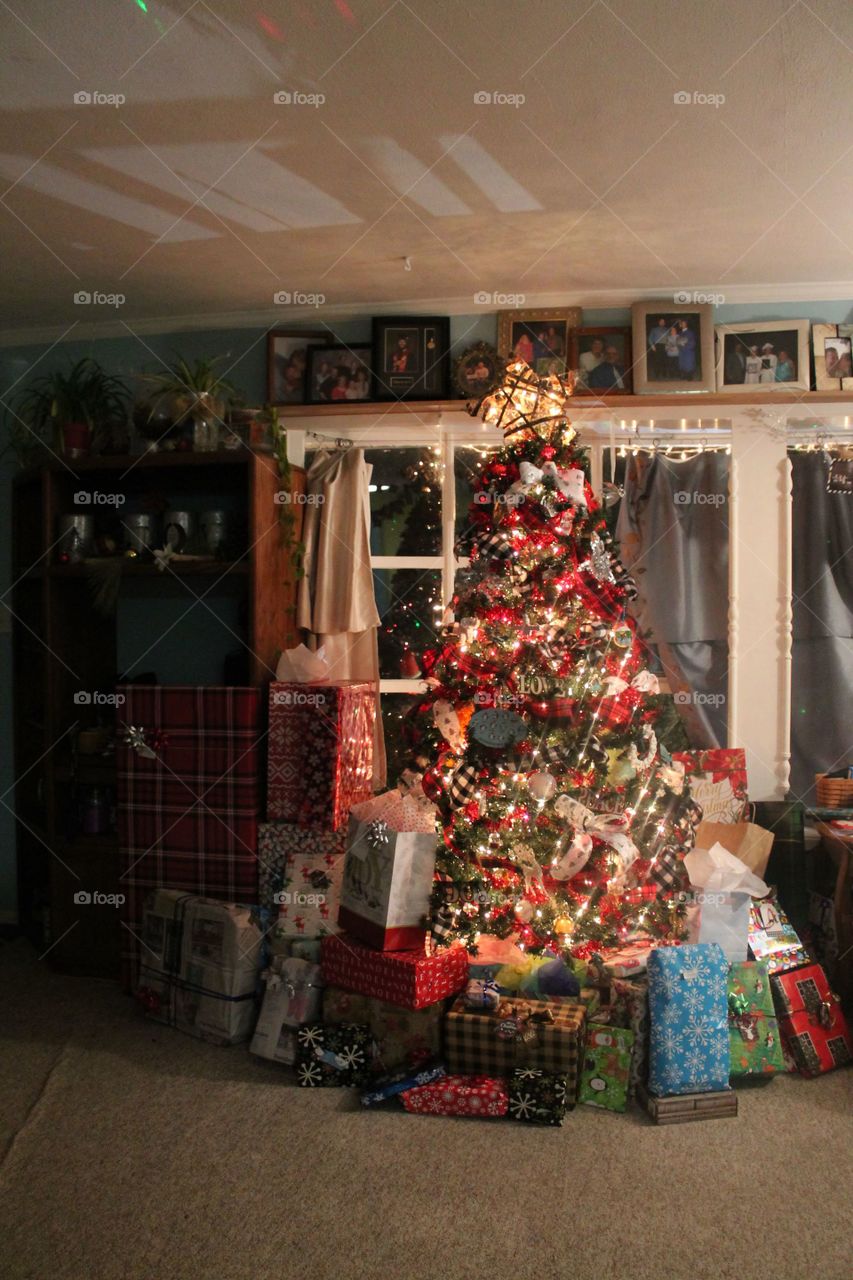 Brightly colored Christmas tree with several wrapped gifts underneath.