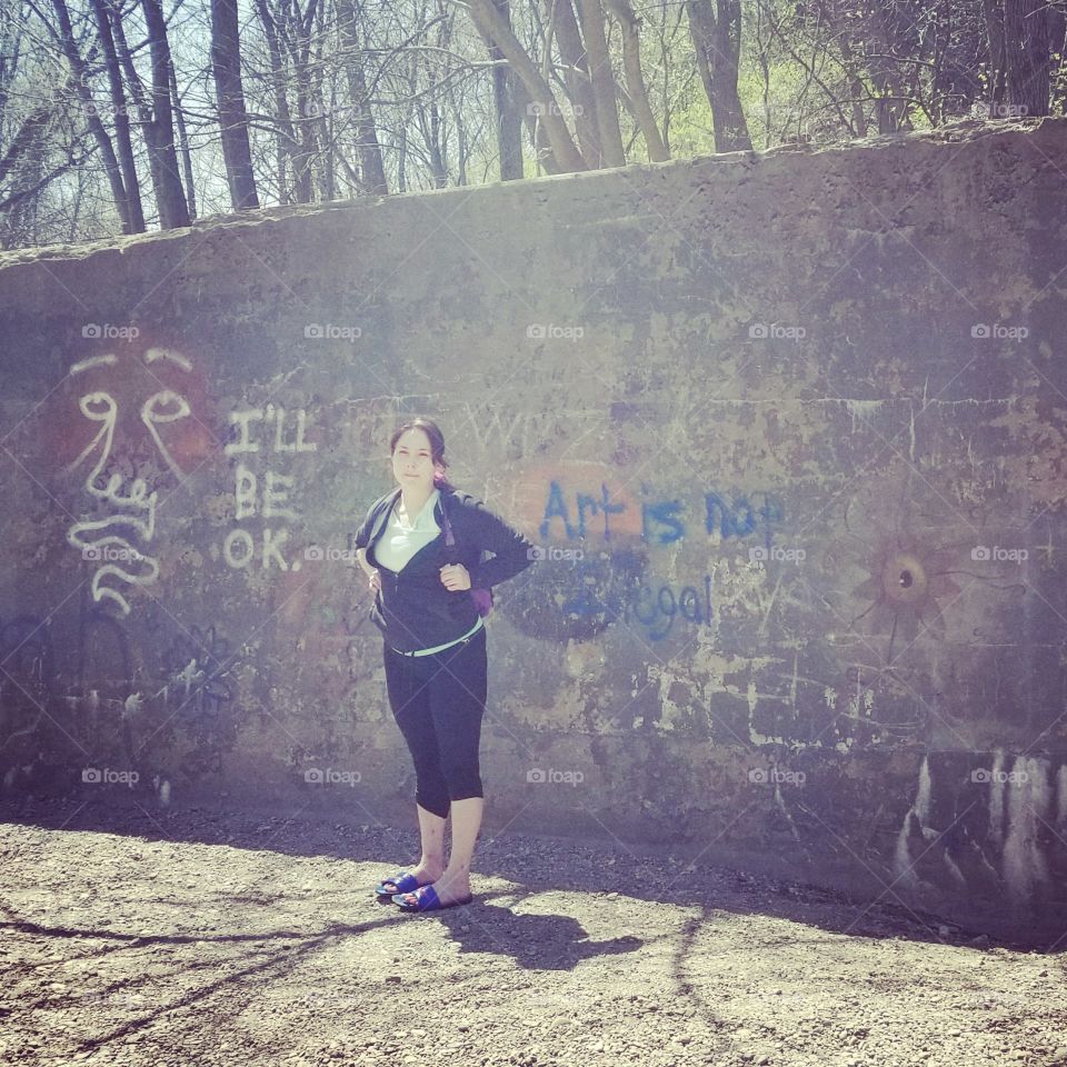 Hiking woman standing by graffiti wall in nature