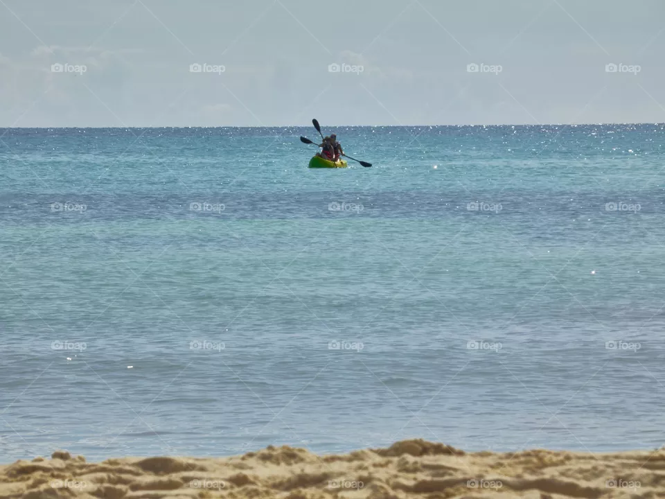 two people practicing canoeing in the caribbean sea on the shores of the beach