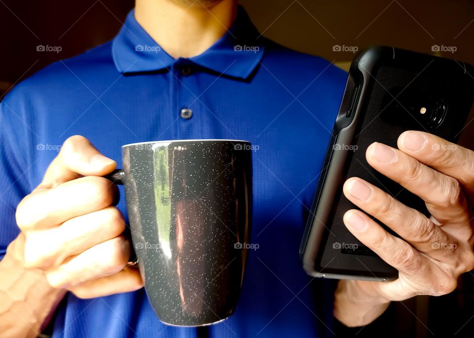 Closeup of a man wearing a polo shirt and drinking coffee while on his cell phone.  (Bright Colors)