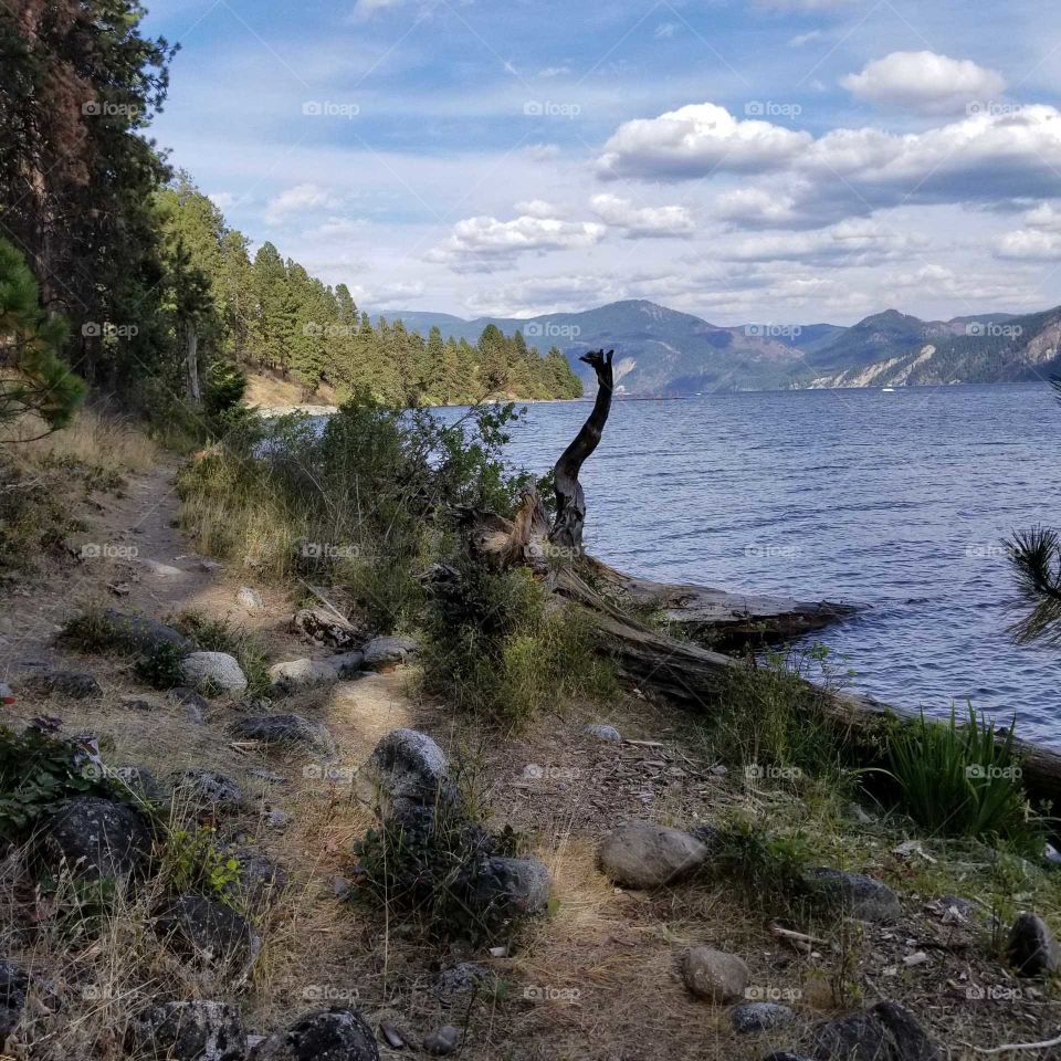 rocky shoreline hiking trail with view of lake and mountain ridges