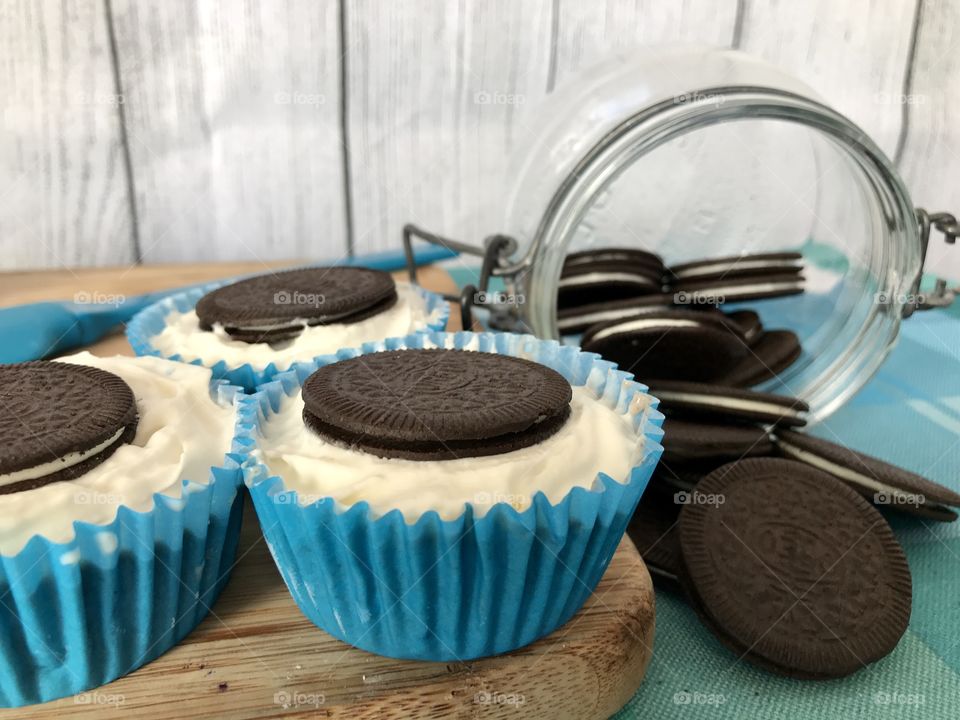 Oreo cookie ice cream cupcakes on a wooden board and white and blue background 