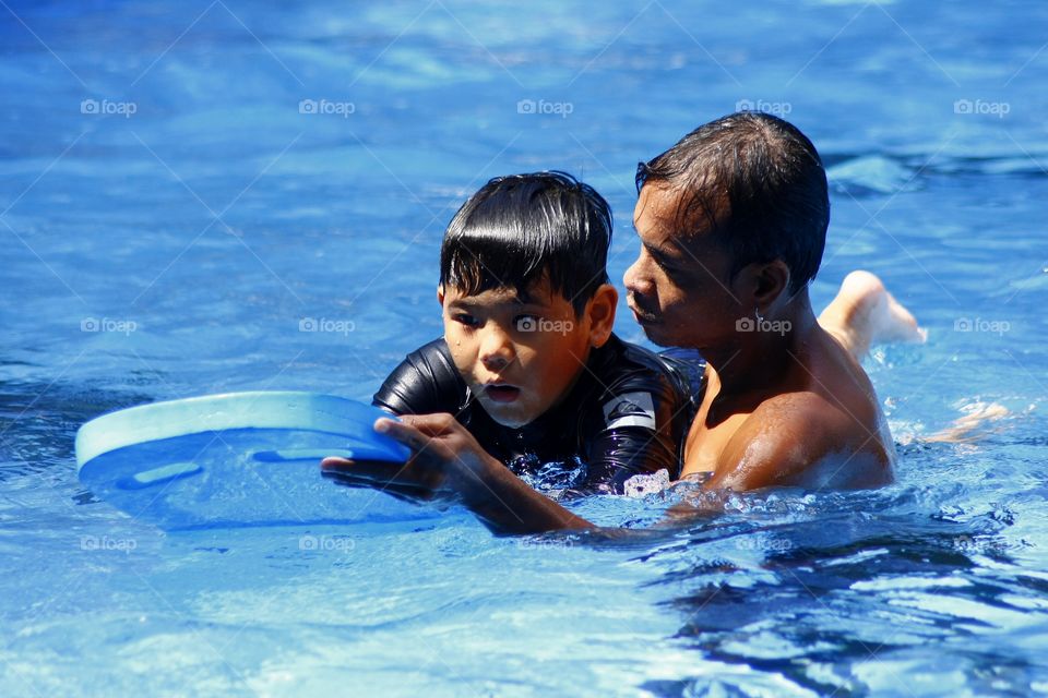 swimming coach teaching a young boy how to swim