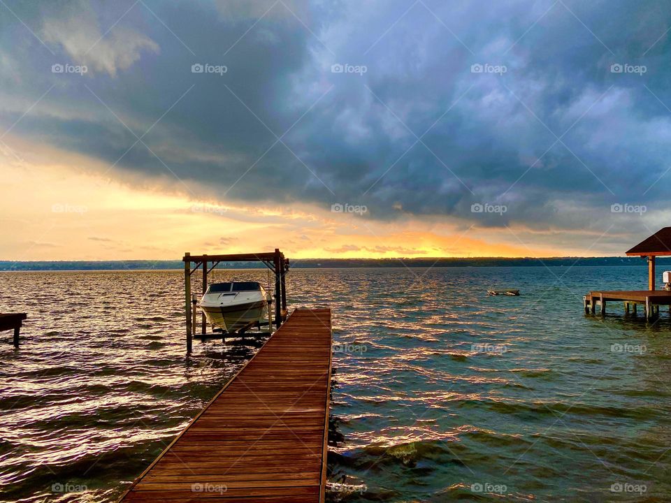 Night clouds slowly creep in to cover the light from the sunset while the waves slowly hit the dock