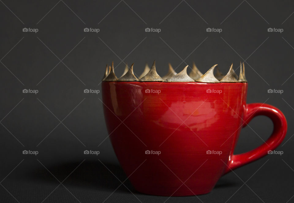 Red cup of coffee and thorns on the edge of the cup