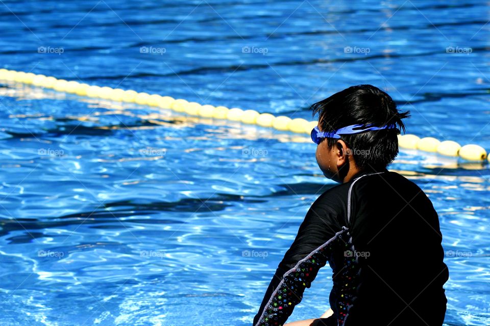 young kid prepares to swim in a swimming pool