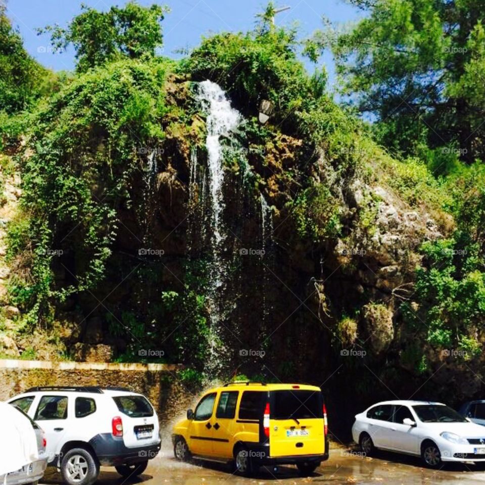 Yellow cab in natures carwash. Taxi under waterfall, Taurus mountains, Turkey