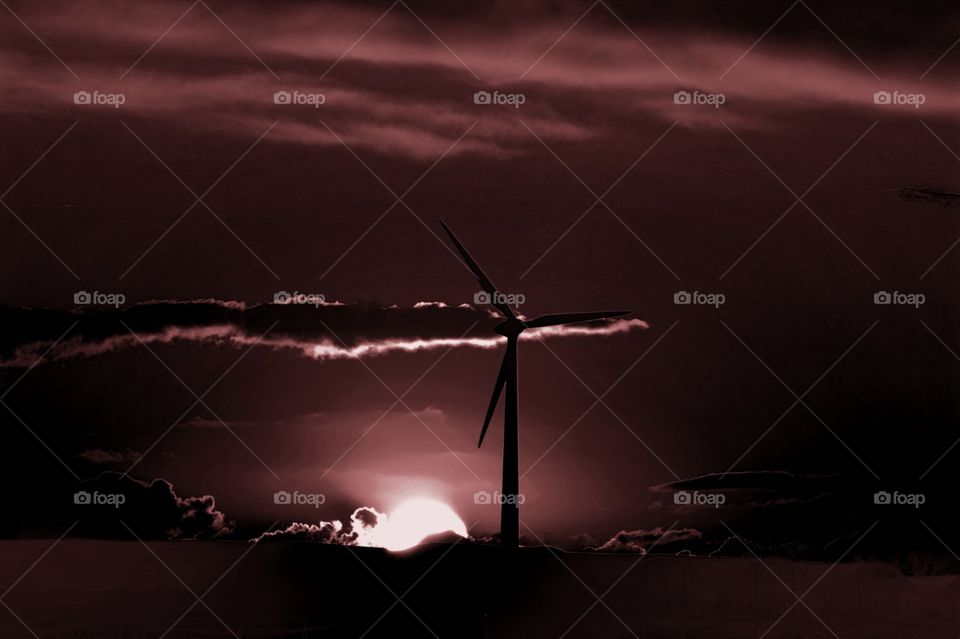 Wind turbine at sunset, dramatic rendering.