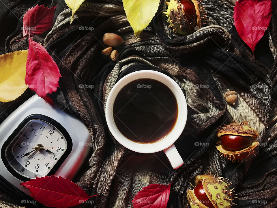 Black coffee cup with autumn leaves and alarm clocks 
