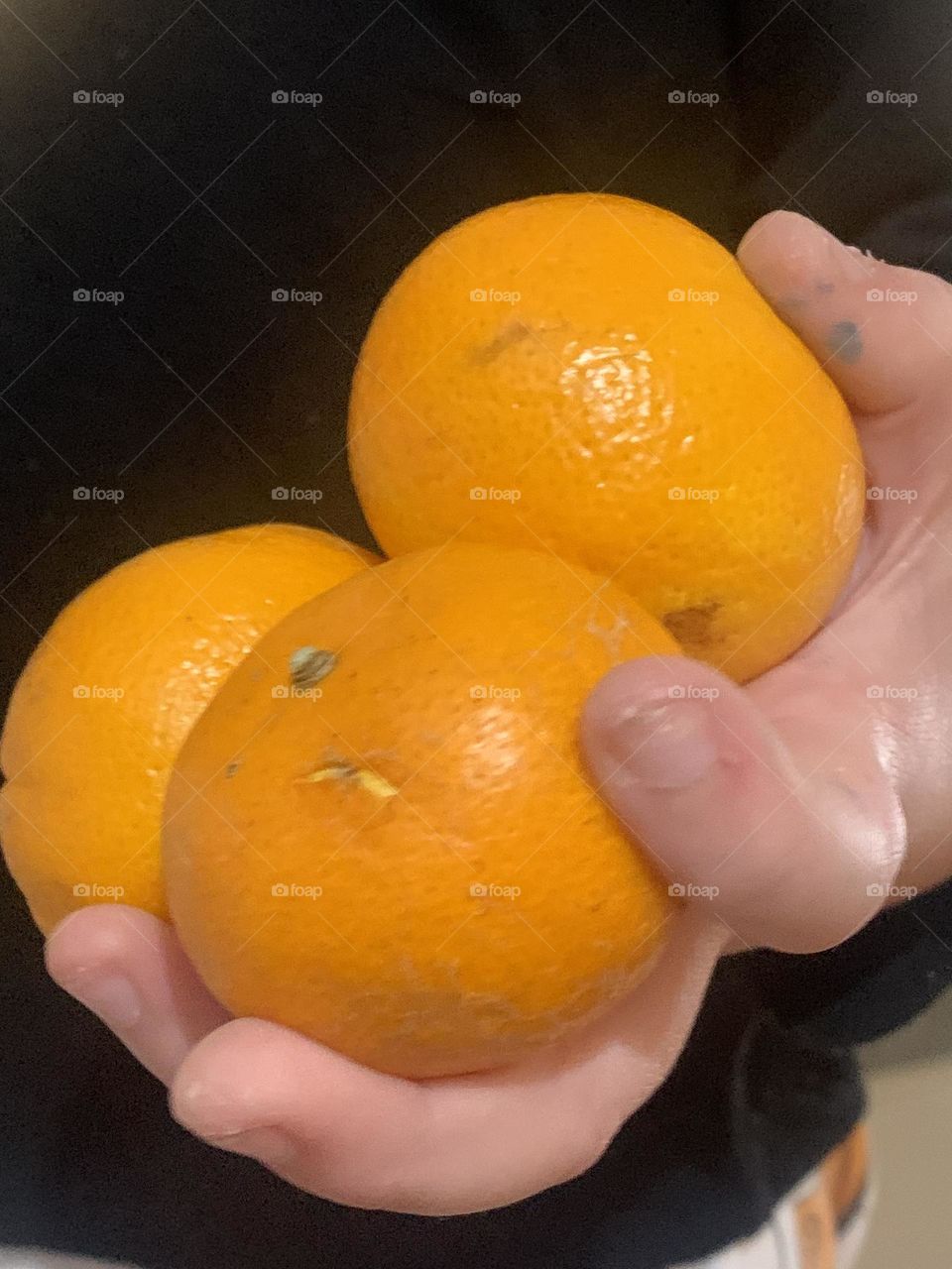 Child holding 3 oranges in his hand 