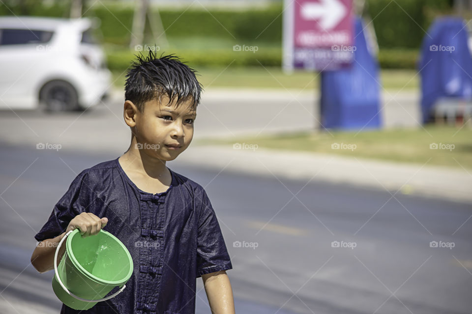 Asian boy holding Plastic bucket play Songkran festival or Thai new year in Thailand.