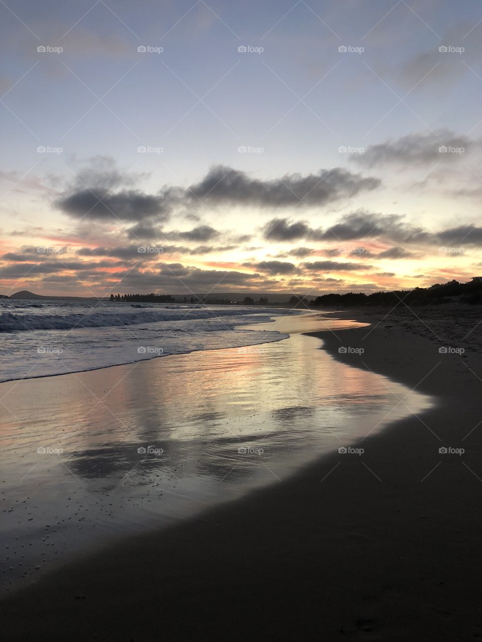 Sunset over Boomer beach with reflections in the sand