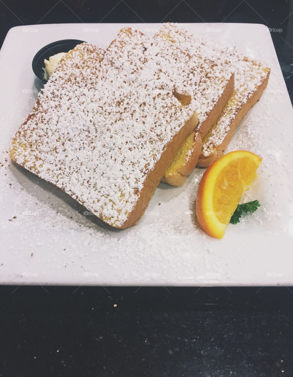 A savory, sweet, and mouthwatering breakfast complete with a sliced lemon and powdered sugar. 