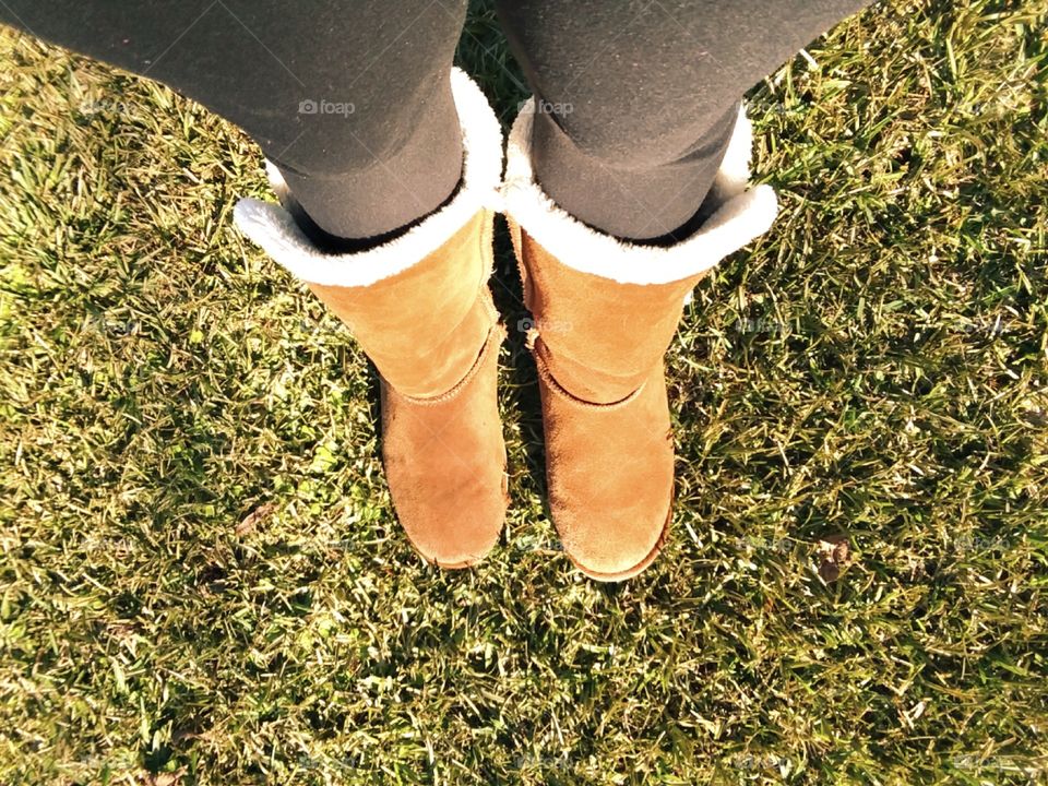 a girl wearing winter boots in the fall grass