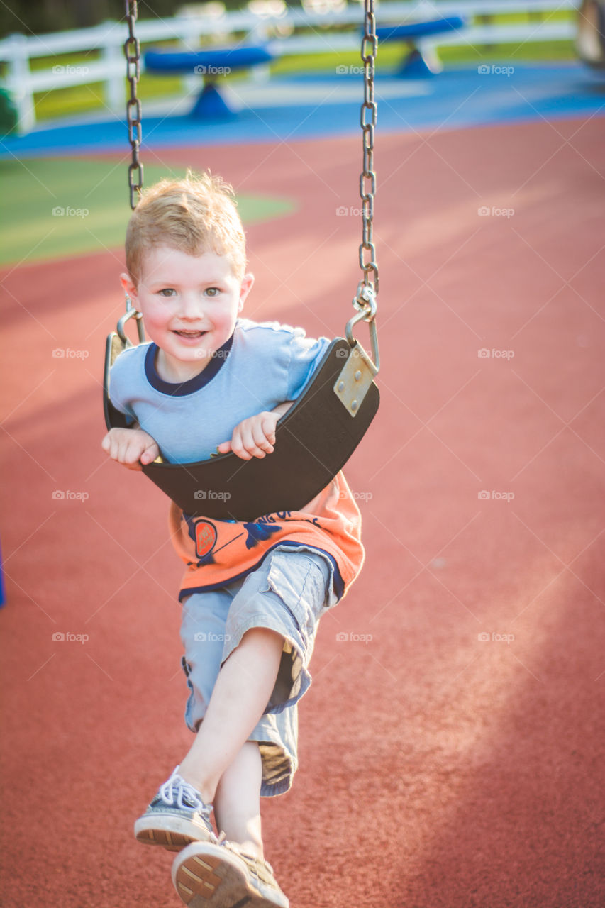 Young Boy Playing in a Swing at a Playground 