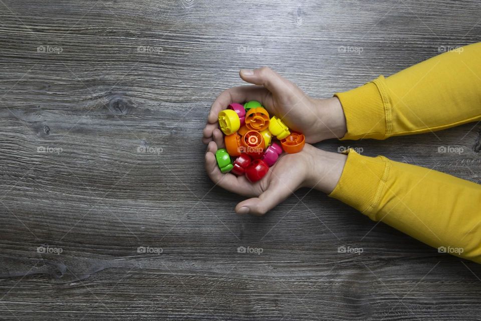 We collect garbage, plastic plugs and plastic to save our planet, nature and the environment. Men's hands lie on a gray wooden surface, which is used as a background or a surface with incident light.